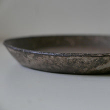 Load image into Gallery viewer, A close-up of a dark, rustic metal tray or shallow dish with a weathered, textured surface, set against a plain light gray background.