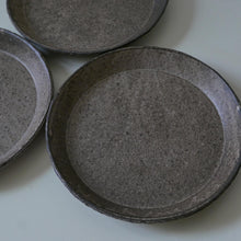 Load image into Gallery viewer, Three round handmade ceramic plates with a textured, speckled dark gray glaze, arranged on a light gray surface.