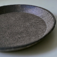 Load image into Gallery viewer, A close-up of a dark gray textured ceramic plate or shallow dish, showing a matte, speckled finish with a shallow depth of field.
