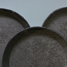 Load image into Gallery viewer, Three round stone planters with a textured gray finish, arranged closely together against a muted light blue-gray background.
