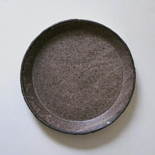Load image into Gallery viewer, A round, shallow dark gray ceramic dish or plate with a textured, speckled glaze, photographed from directly above on a plain off-white background.
